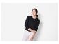 Modèle féminin portant un cardigan noir et un pantalon blanc.