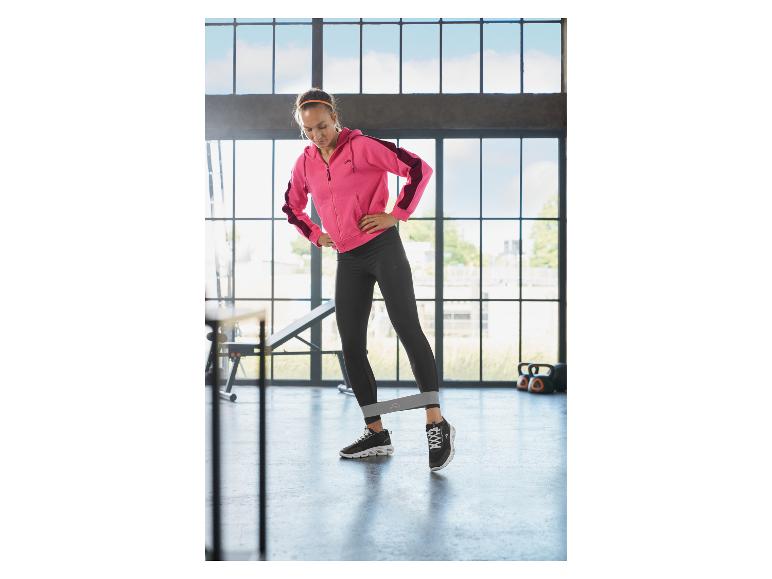 Femme faisant de l'exercice avec une bande de résistance dans une salle de sport.