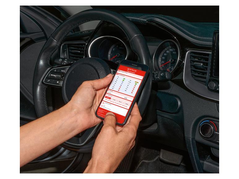 Une personne utilise un smartphone avec l'application ULTIMATE pour le diagnostic automobile dans une voiture.