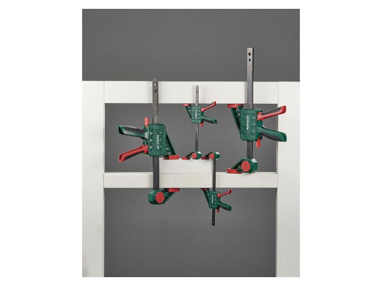 Serre-joints de différentes tailles, fixés sur un cadre blanc.