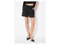 Femme en short noir à cordon, crop top et veste, avec des chaussures noires à bout pointu.