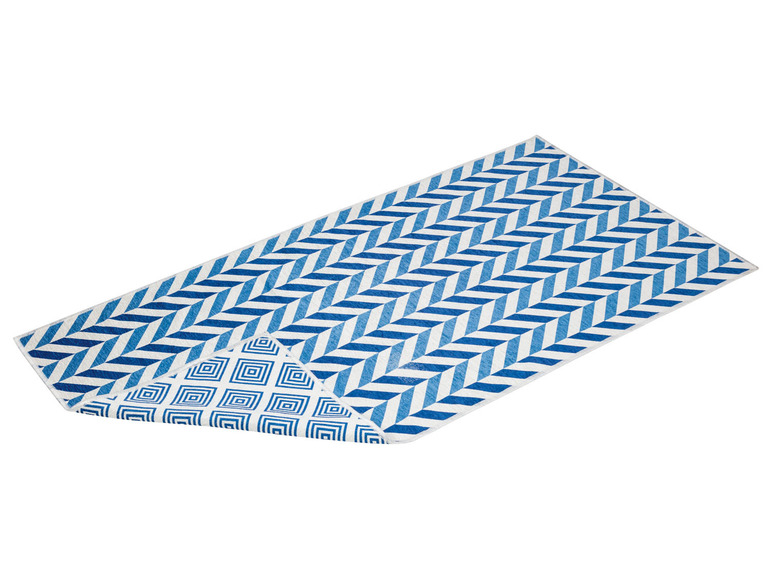 Une serviette de plage bleue et blanche avec un motif chevron et des carrés.