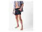 Un homme en chemise rayée et short de bain noir.