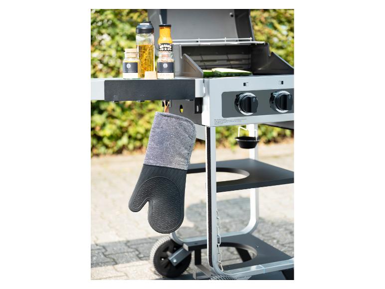 Gant de cuisine accroché à un barbecue avec des épices et des sauces.