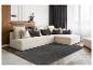 Canapé d'angle beige avec coussins et tapis gris foncé dans un salon.
