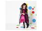 Une fille en robe rose et noire avec une cape pose devant un fond à pois colorés.