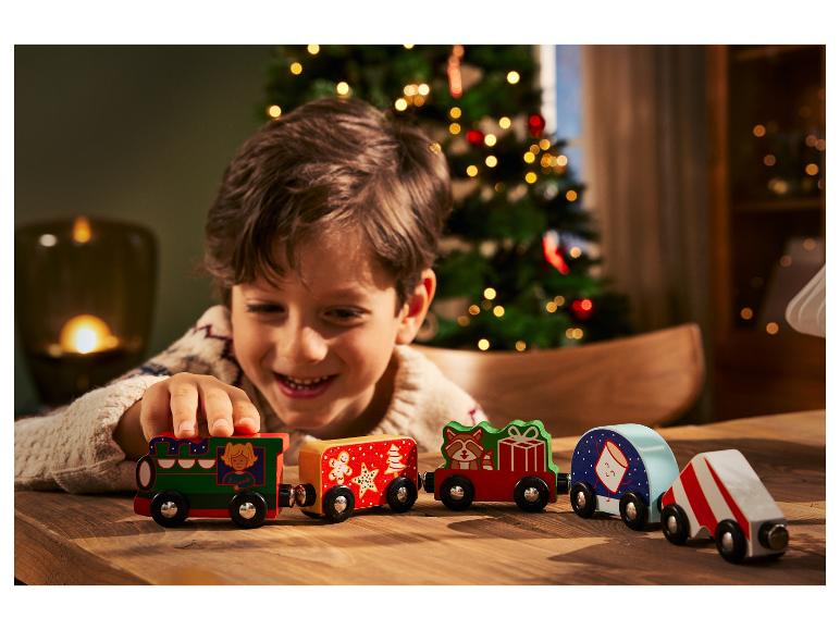 Un enfant joue avec un train en bois sur le thème de Noël.