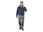 Un homme porte une veste de travail bleue et un pantalon de travail gris.