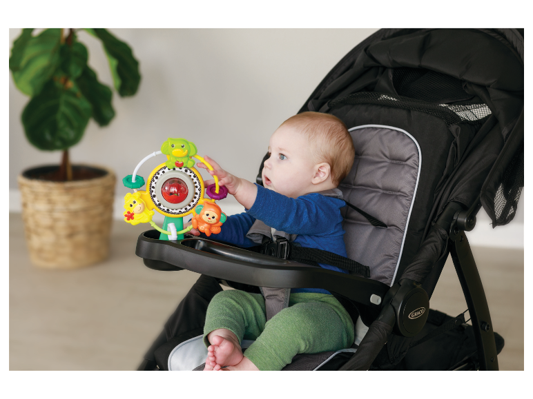 Bébé dans une poussette Graco avec un jouet d'activité.