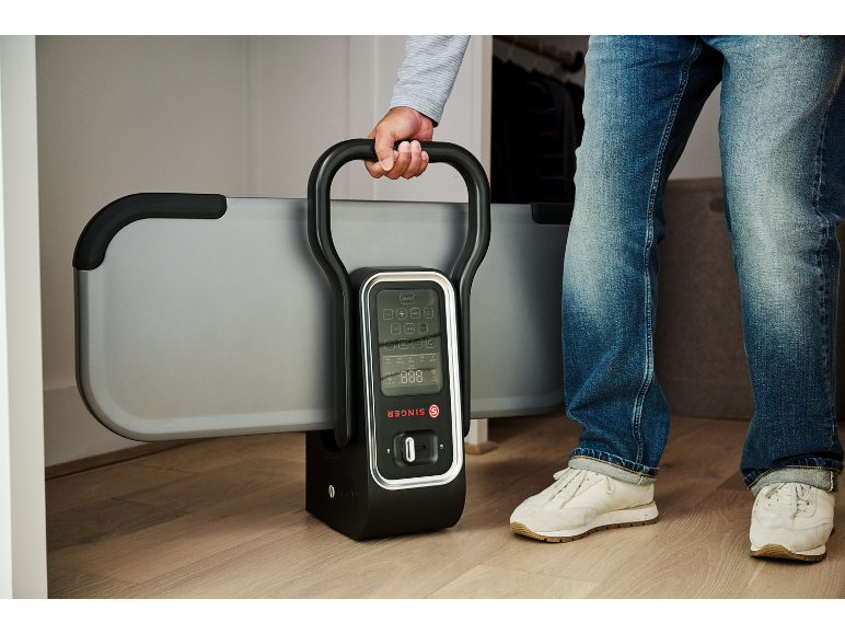 Un homme tient un appareil de fitness pliable avec un écran numérique.