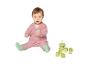 Bébé en cardigan rose et chaussettes vertes, jouant avec des blocs de construction et un jouet à empiler.