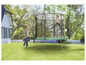 Une fille saute sur un trampoline dans le jardin.