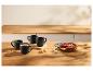 Tasses noires avec boissons et tarte aux fruits sur une table en bois.