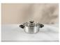 Casserole en acier inoxydable avec couvercle en verre sur une table en marbre blanc.