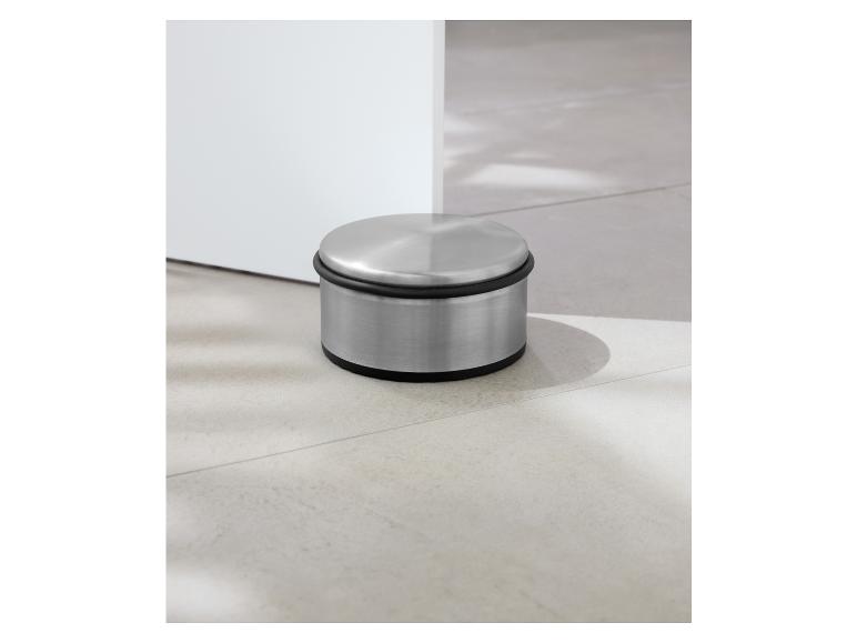 Un butoir de porte en acier inoxydable sur un sol en carrelage.