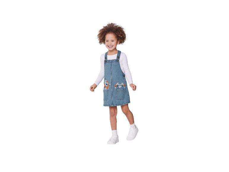 Petite fille portant une robe en jean brodée et des baskets blanches.
