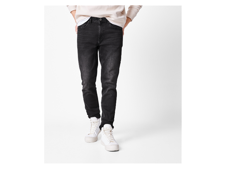 Jeans noirs ajustés portés avec des baskets blanches.