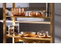 Batterie de cuisine en cuivre sur une étagère en bois, avec des bocaux de légumineuses.