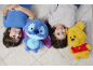 Deux enfants souriants allongés sur un tapis avec deux peluches, une bleue et une jaune.