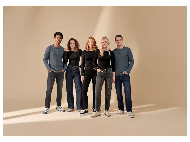 Cinq personnes en hauts à manches longues et jeans, souriant à la caméra.