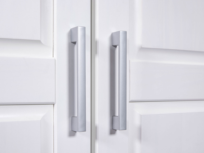 Deux poignées de porte argentées sur une porte blanche.