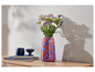 Des fleurs dans un vase rouge et bleu à pois, deux objets décoratifs bleus et des livres sur une table en bois.
