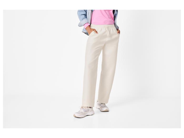 Personne en t-shirt rose, veste en jean, pantalon beige et baskets.