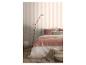 Chambre à coucher avec papier peint rayé, lit avec literie rose et blanche, et lampadaire.