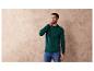 Un homme portant un pull vert et un jean bleu.