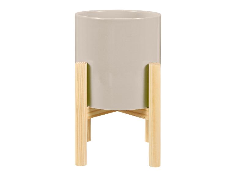 Un pot de fleurs gris sur un support en bois.