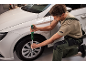 Un homme utilise une clé dynamométrique pour serrer la roue d'une voiture blanche.