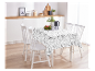 Table de salle à manger blanche avec nappe à motifs et chaises en bois.