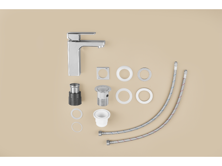 Ensemble de robinet de salle de bain avec robinet chromé, bonde et tuyaux sur fond beige.