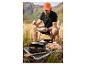 Homme mangeant en camping avec ustensiles de cuisine et nourriture sur la table.