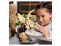 Une fille assemble un squelette de dinosaure LEGO, avec une figurine LEGO à côté d'elle.