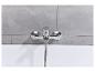Robinet de baignoire chromé avec douchette, sur fond de carrelage gris.