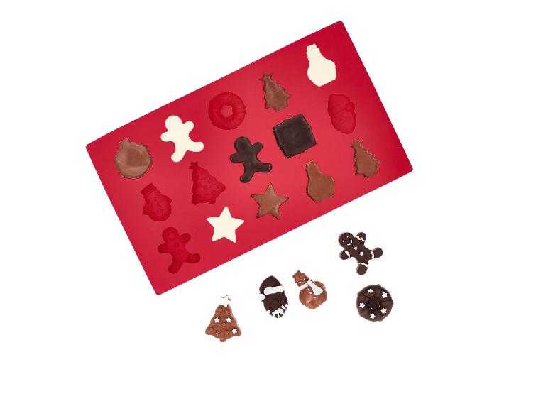 Moule en silicone rouge avec des chocolats de Noël et quelques chocolats séparés.