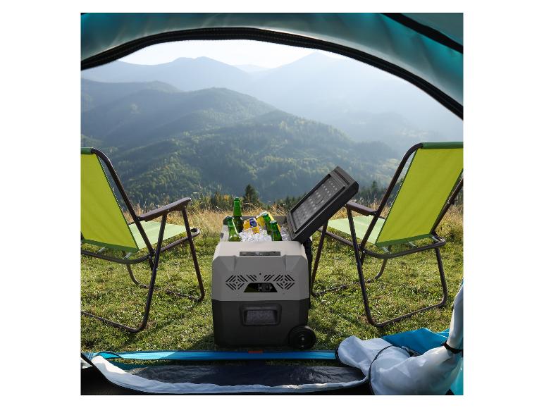 Glacière portable avec boissons et chaises de camping devant un paysage montagneux.