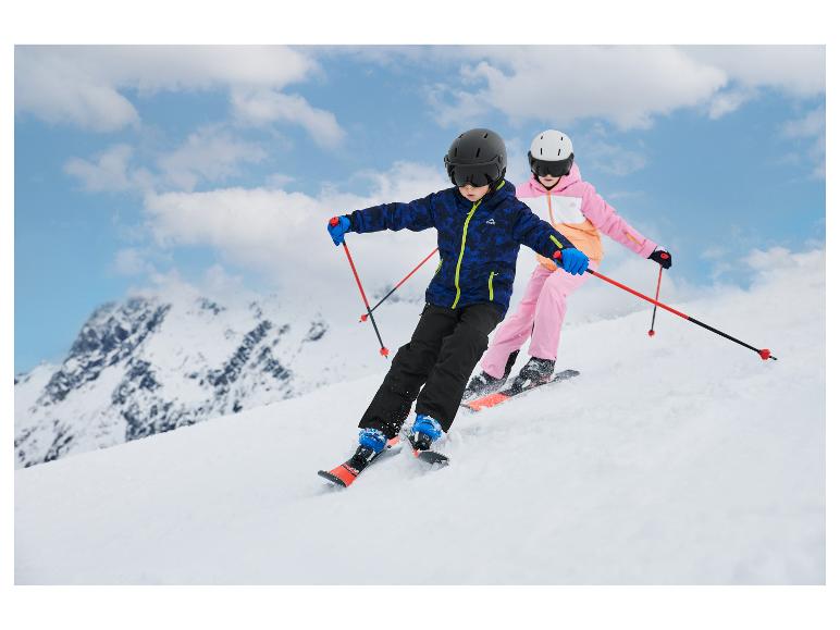 Deux enfants skient sur une pente en montagne, portant des vestes et pantalons de ski.