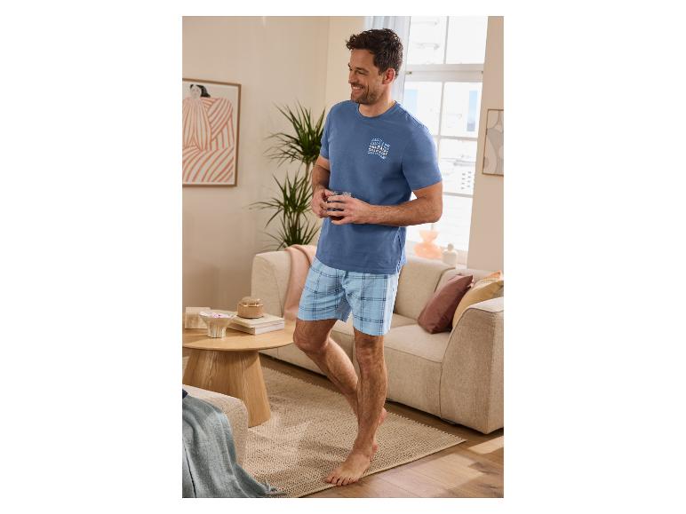 Homme en pyjama bleu avec le texte « CALL IT A DAY » dans un salon.