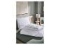Oreiller matelassé blanc et couette pliée sur un lit avec un drap vert