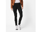 Femme en veste marron, t-shirt blanc, jean noir et baskets blanches.