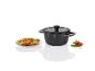 Une casserole noire avec un couvercle et une assiette avec des pâtes, des tomates et du basilic.