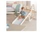 Enfant assis sur un toboggan en bois avec échelle d'escalade dans une chambre d'enfant.