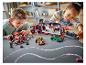 Deux enfants jouent avec des ensembles LEGO Speed Champions, dont un camion de transport et des voitures de course.
