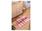 Tapis de bain rayé rose et blanc avec l'inscription « Ciao Bella » sur un parquet.