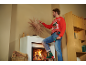 Homme en pull de Noël accrochant une décoration au-dessus de la cheminée avec une visseuse sans fil.
