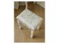 Tabouret de coiffeuse blanc avec assise à motif floral gris clair sur un parquet.
