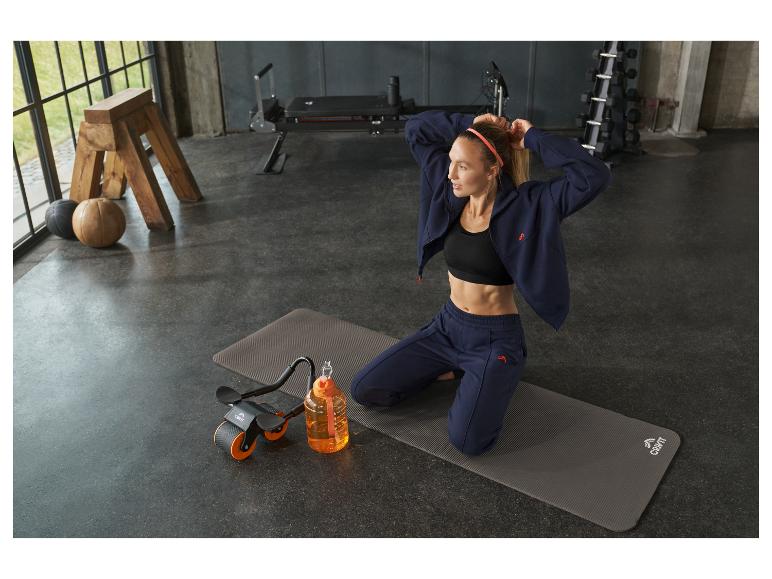 Femme en tenue de sport bleue avec une roue abdominale et une bouteille d'eau.