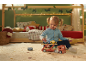 Fille joue avec un camion transporteur de voitures en bois dans une chambre d'enfant décorée pour Noël.